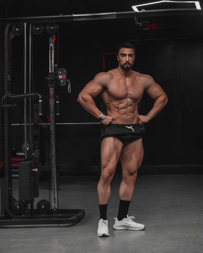 Athletic male posing in a gym showcasing muscle definition and fitness.