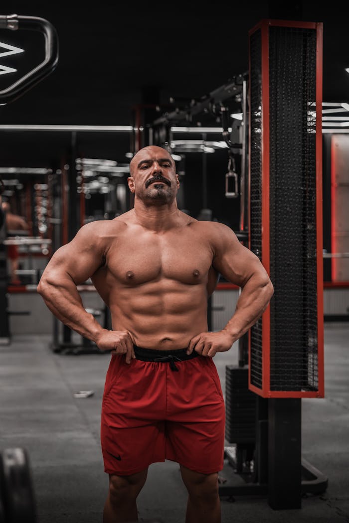 Athletic man showcasing physique in a gym, emphasizing fitness and strength.